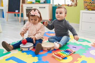 Adorable boy and girl playing xylophone and tambourine at kindergarten
