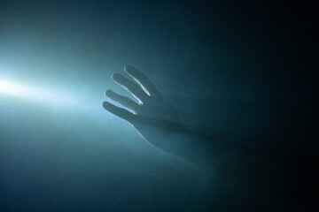 Hand being illuminated by light in the smoke