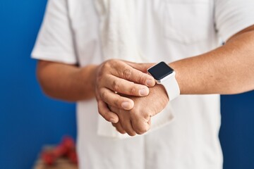 Young latin man touching stopwatch at sport center