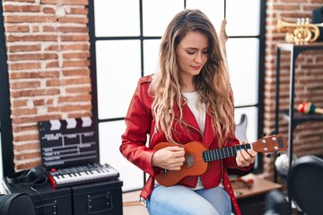 Fototapeta na wymiar Young woman musician playing ukulele at music studio
