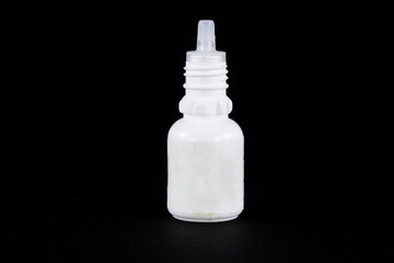 Medical white plastic squeezable bottle, also called squeezer bottle, isolated on a black background, used to store medicine liquids such as eye drops and nasal drops.
