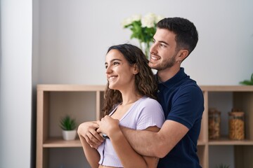 Young hispanic couple hugging each other standing at home