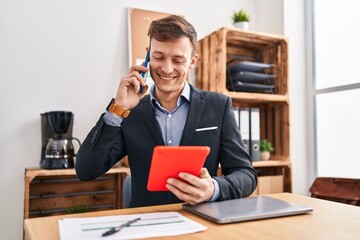 Obraz premium Young man business worker talking on smartphone using touchpad at office