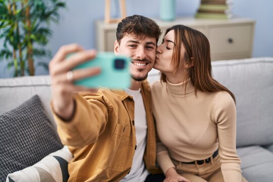 Mand and woman couple make selfie by smartphone sitting on sofa at home