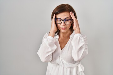 Middle age hispanic woman standing over isolated background with hand on head for pain in head because stress. suffering migraine.