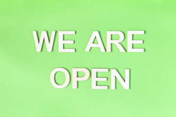 We are open quote, welcome sign for business or caffe, wooden letters on green background