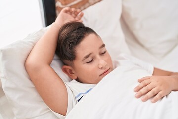 Fototapeta na wymiar Adorable hispanic boy lying on bed sleeping at bedroom