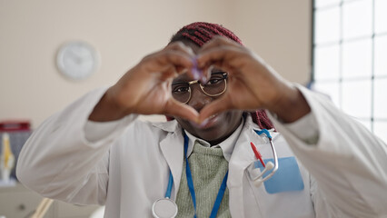 African woman with braided hair doctor smiling doing heart gesture with hands at clinic