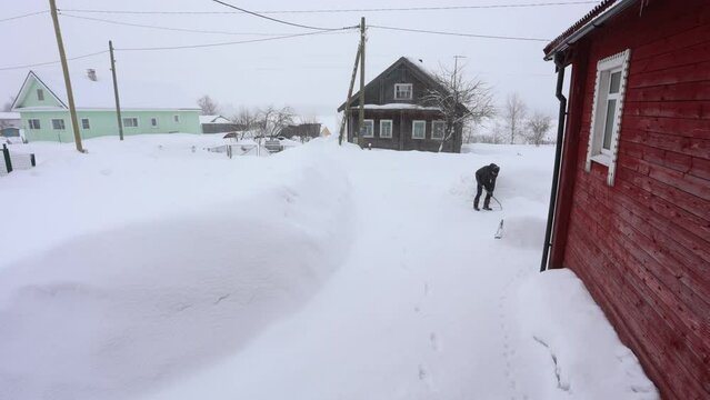 Villager is clearing snow from house adjacent to country withcold climate onwinter day.