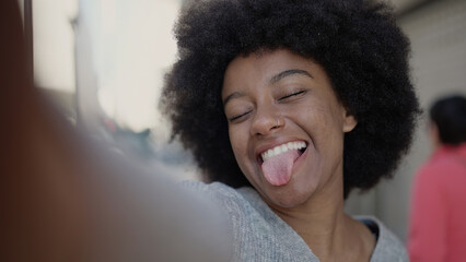 African american woman making selfie by camera doing with tongue out of mouth at street © Krakenimages.com
