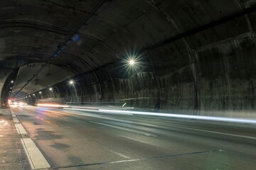 Trail of the headlights of cars that pass quickly through the highway tunnel road towards the...