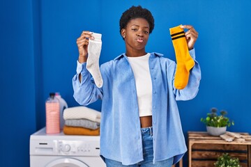 African american woman holding clean andy dirty socks looking at the camera blowing a kiss being...