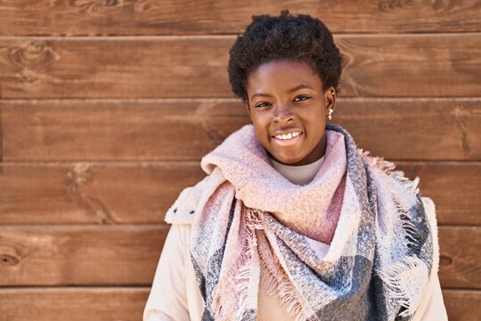 African american woman standing over wood background looking positive and happy standing and smiling with a confident smile showing teeth