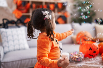 Adorable hispanic girl having halloween party playing with soap bubbles at home