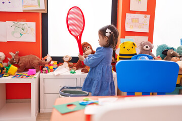 Adorable hispanic girl playing with tennis racket at kindergarten