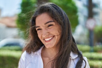 Young hispanic woman smiling confident looking to the side at park