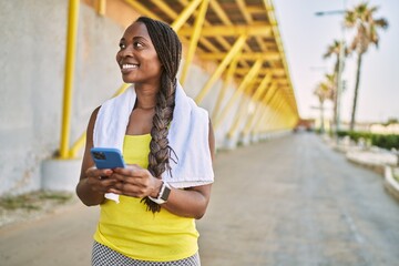 African american woman wearing sportswear using smartphone at street