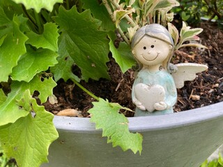 Kleiner Engel mit Herz in einem Blumentopf auf dem Friedhof