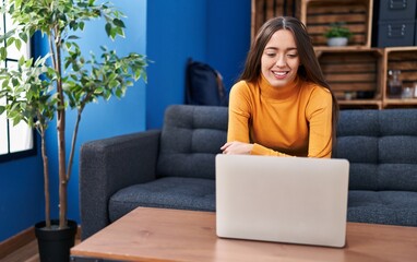 Obraz premium Young beautiful hispanic woman using laptop sitting on sofa at home