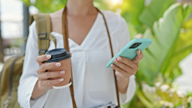 Young beautiful hispanic woman tourist using smartphone drinking coffee at park