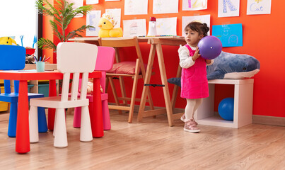 Adorable hispanic girl playing with ball at kindergarten