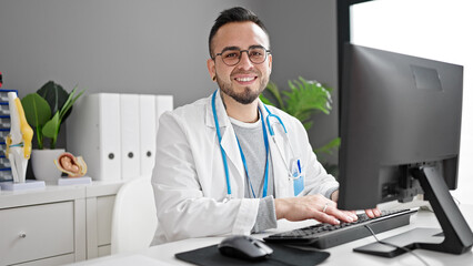 Hispanic man doctor using computer working at the clinic