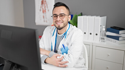 Hispanic man doctor using computer working at the clinic