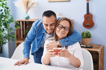 Man and woman mother and son drinking coffee hugging at home