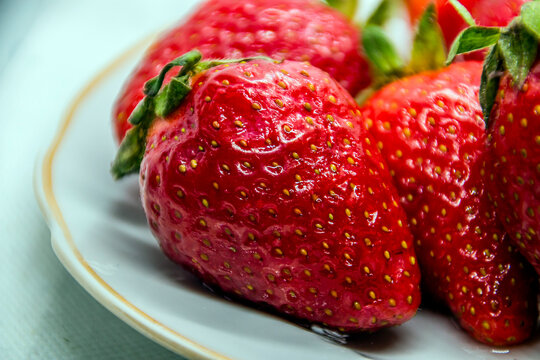 Red Strawberries Lie On A White Plate Close-up