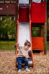 Little toddler boy slides down the slide in the playground