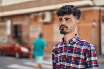 Young hispanic man looking to the sky with relaxed expression at street