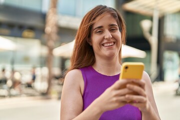 Young woman smiling confident using smartphone at street