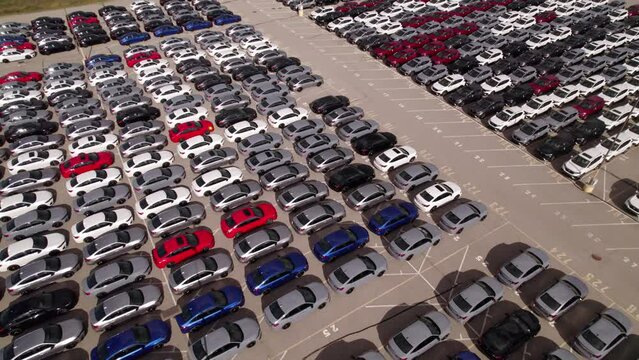 New hybrid EV cars stock parking. Aerial of parking lot of brand new cars for sale and transportation at manufacturer plant, automobile industry.