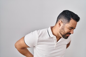 Young hispanic man with beard wearing casual clothes over white background suffering of backache, touching back with hand, muscular pain
