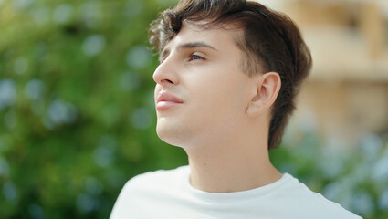 Non binary man looking to the side with serious expression at park