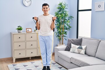 Young non binary man smiling confident using elastic band training at home