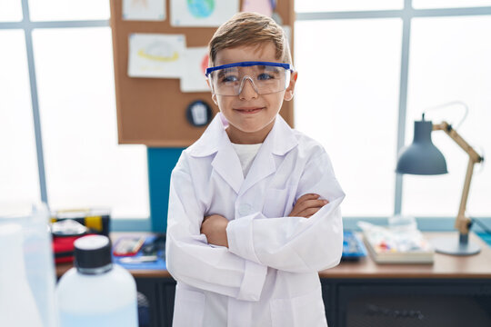 Adorable hispanic boy student smiling confident standing with arms crossed gesture at laboratory classroom
