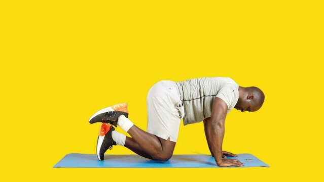 Sportive african man doing glute kickback exercise on a mat