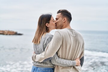 Man and woman couple hugging each other kissing at seaside