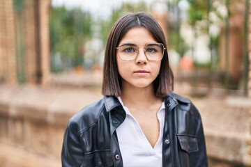 Young beautiful hispanic woman standing with serious expression at street