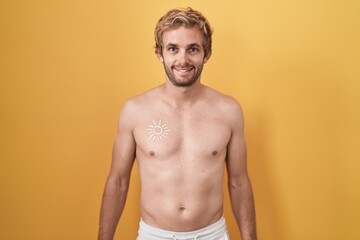 Fototapeta premium Caucasian man standing shirtless wearing sun screen with a happy and cool smile on face. lucky person.