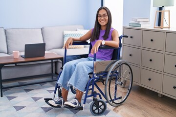Young hispanic woman sitting on wheelchair at home with a happy and cool smile on face. lucky...
