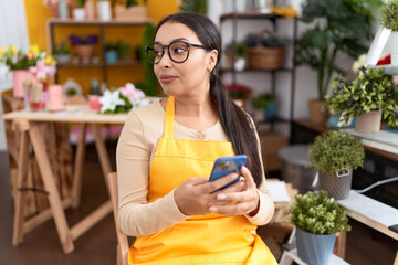 Young arab woman florist smiling confident using smartphone at flower shop