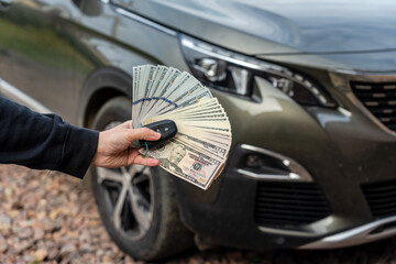 Person with money and car key standing front car. Insurance, loan concept. Deal of buy or rent new...