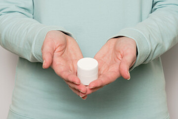 Woman's hands hold plastic jar (container). Cosmetic product.
