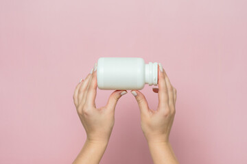 Bottle of pills or vitamins in woman's hand. Product branding mockup.