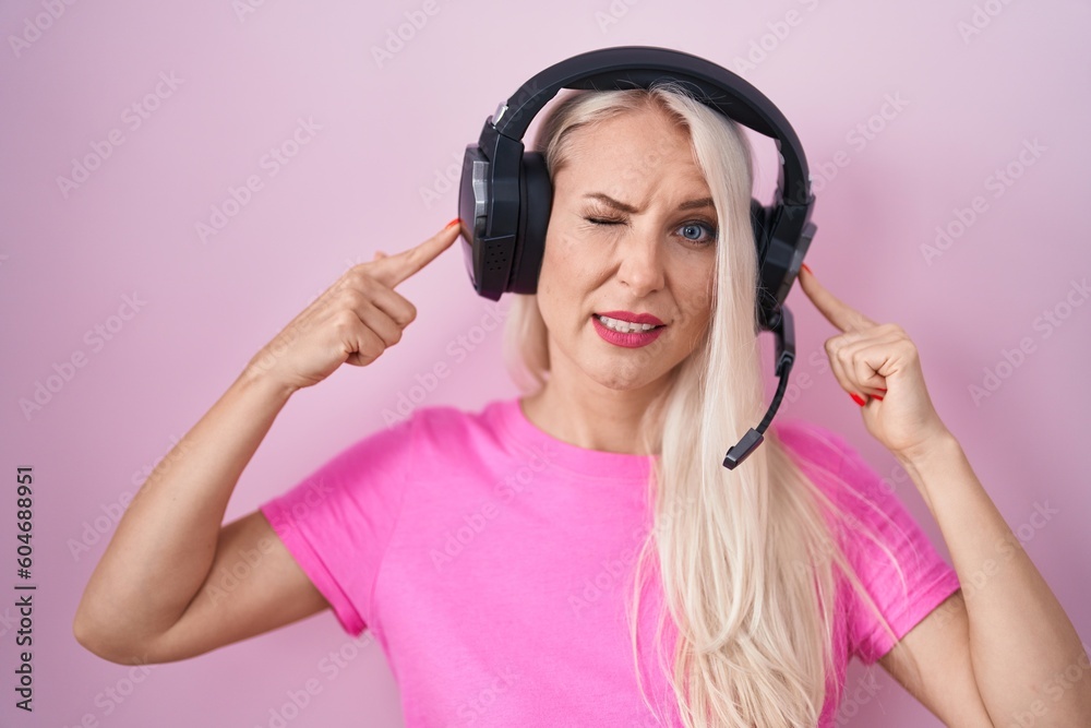 Canvas Prints caucasian woman listening to music using headphones covering ears with fingers with annoyed expressi