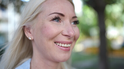 Young blonde woman smiling confident looking to the side at park