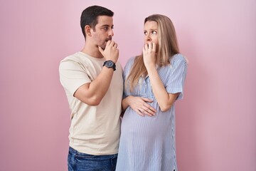 Young couple expecting a baby standing over pink background looking stressed and nervous with hands...