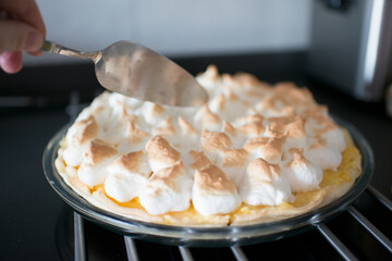 Human hand about to serve a homemade lemon pie
